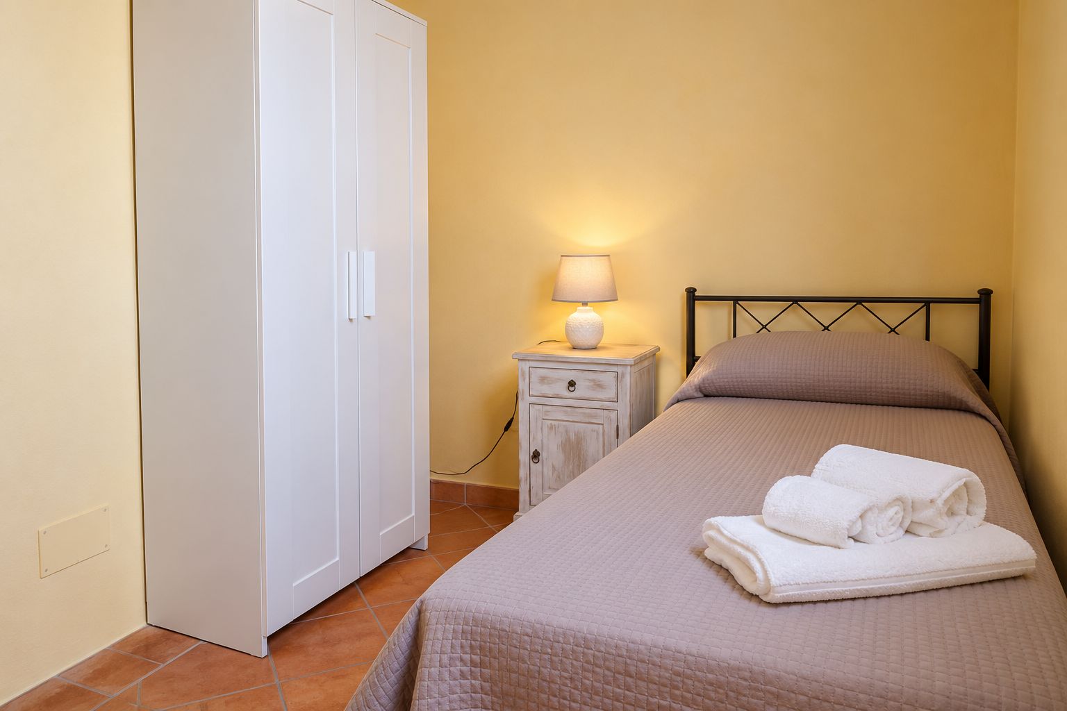 Une chambre à coucher avec un lit, une table de chevet avec une lampe et une armoire.
