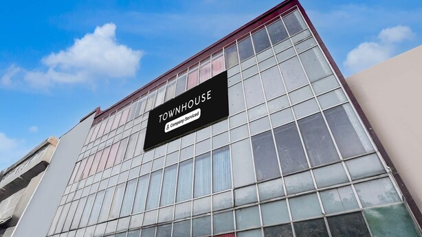 A building with a large glass facade, a sign reading 'TOWNHOUSE Company Serviced,' and a storefront with colorful curtains. - Saver Single Near Max Hospital (New Delhi)