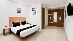 A modern hotel room with a large bed, a nightstand, a TV, and a wardrobe. - Saver Single Near Max Hospital (New Delhi)