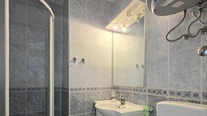 Un bagno con doccia, lavandino, water e specchio.