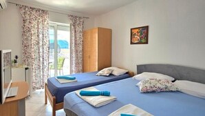 Habitación de hotel con dos camas, un escritorio, un televisor y una ventana con cortinas.