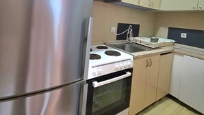 Una cocina con electrodomésticos de acero inoxidable, gabinetes color beige, una estufa y un lavamanos.