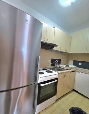 Eine Küche mit Edelstahlgeräten, beigen Schränken, einem Herd und einem Spülbecken.