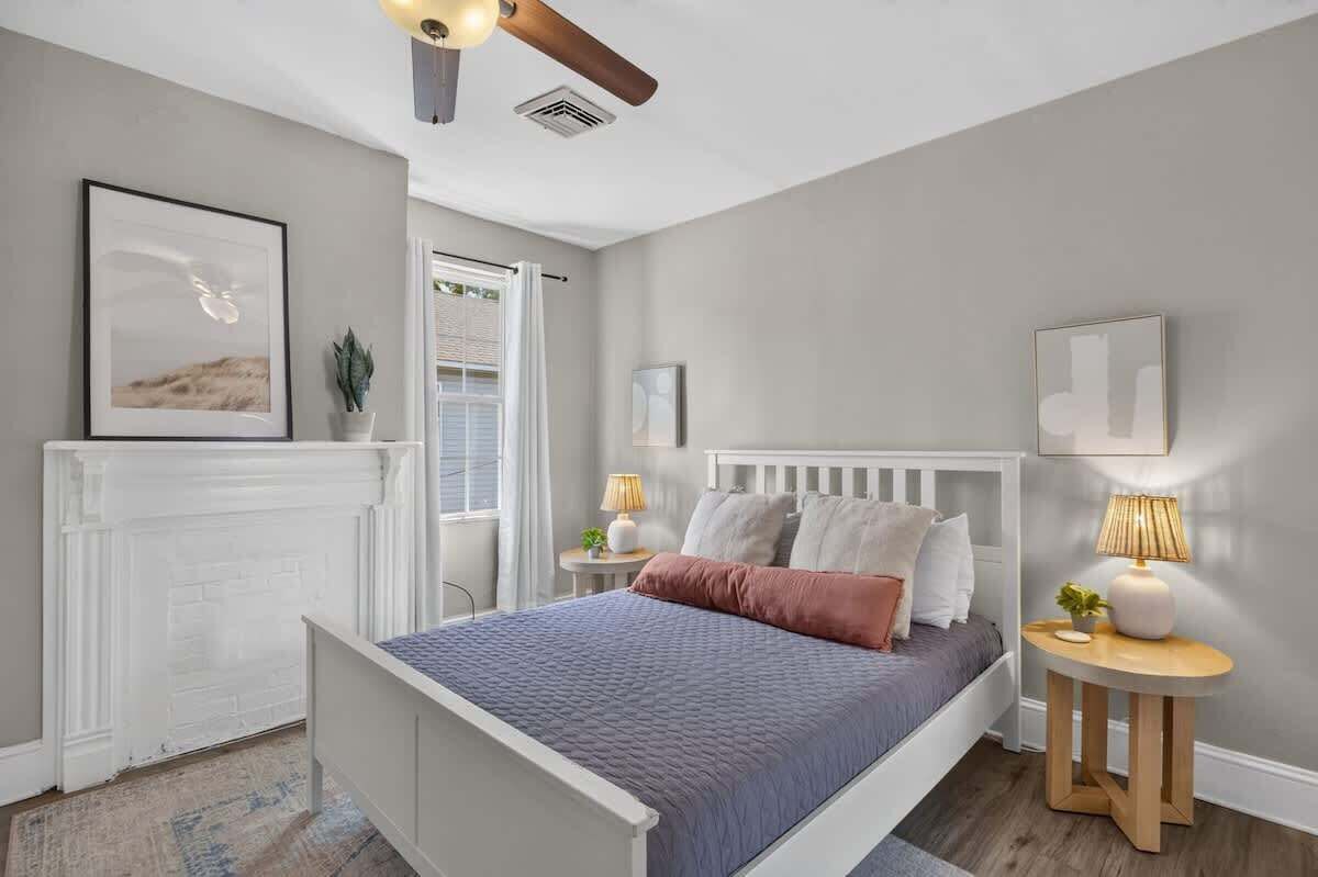 A bedroom with a bed, bedside tables, a radiator, and a window.