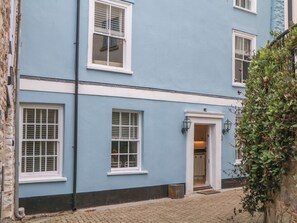A two-story building with multiple windows, a door, and a small garden area. - Dennings House, Mayors Avenue (Dartmouth)