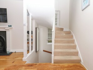 A staircase with beige carpeted steps, white walls, and a wooden floor. - Dennings House, Mayors Avenue (Dartmouth)