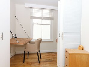 Une pièce comprenant un bureau en bois, une chaise, une fenêtre avec des stores et un meuble en bois.