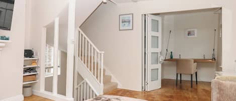 A spacious living area with a staircase, a dining area, and a small kitchenette.