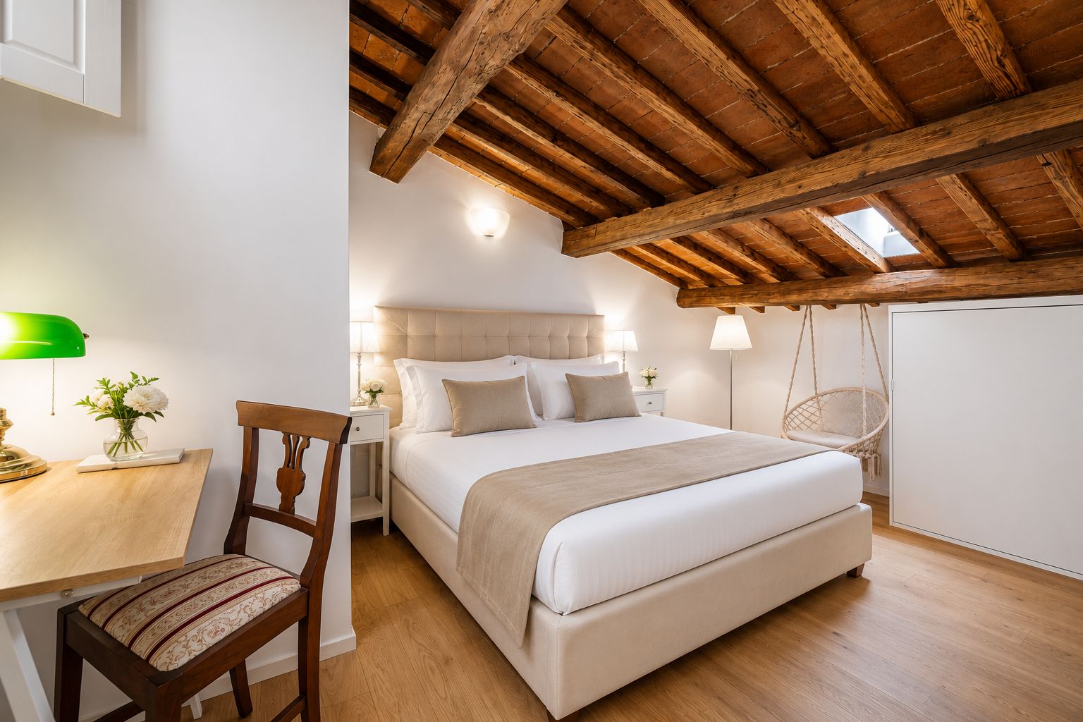 Ein Schlafzimmer mit Holzbalkendecke, einem Bett, einem Schreibtisch mit Stuhl und einem Hängestuhl.