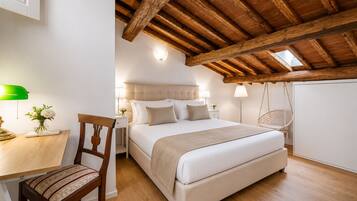 Ein Schlafzimmer mit Holzbalkendecke, einem Bett, einem Schreibtisch mit Stuhl und einem Hängestuhl.