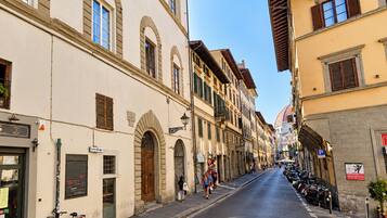 Una calle con edificios, una bicicleta y gente caminando.