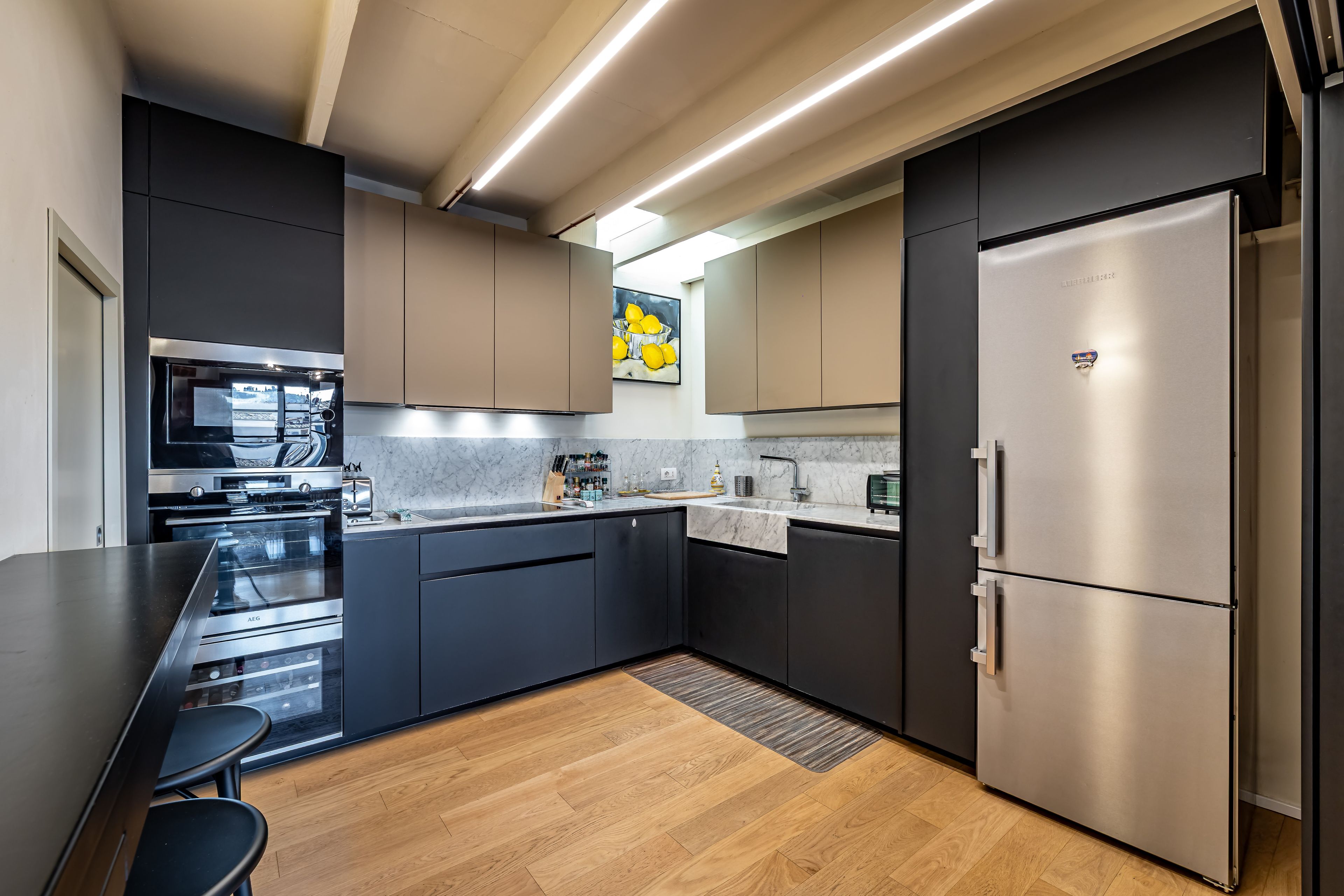 Una cocina moderna con armarios oscuros, electrodomésticos de acero inoxidable y una encimera de mármol.