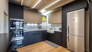 Una cocina moderna con armarios oscuros, electrodomésticos de acero inoxidable y una encimera de mármol.
