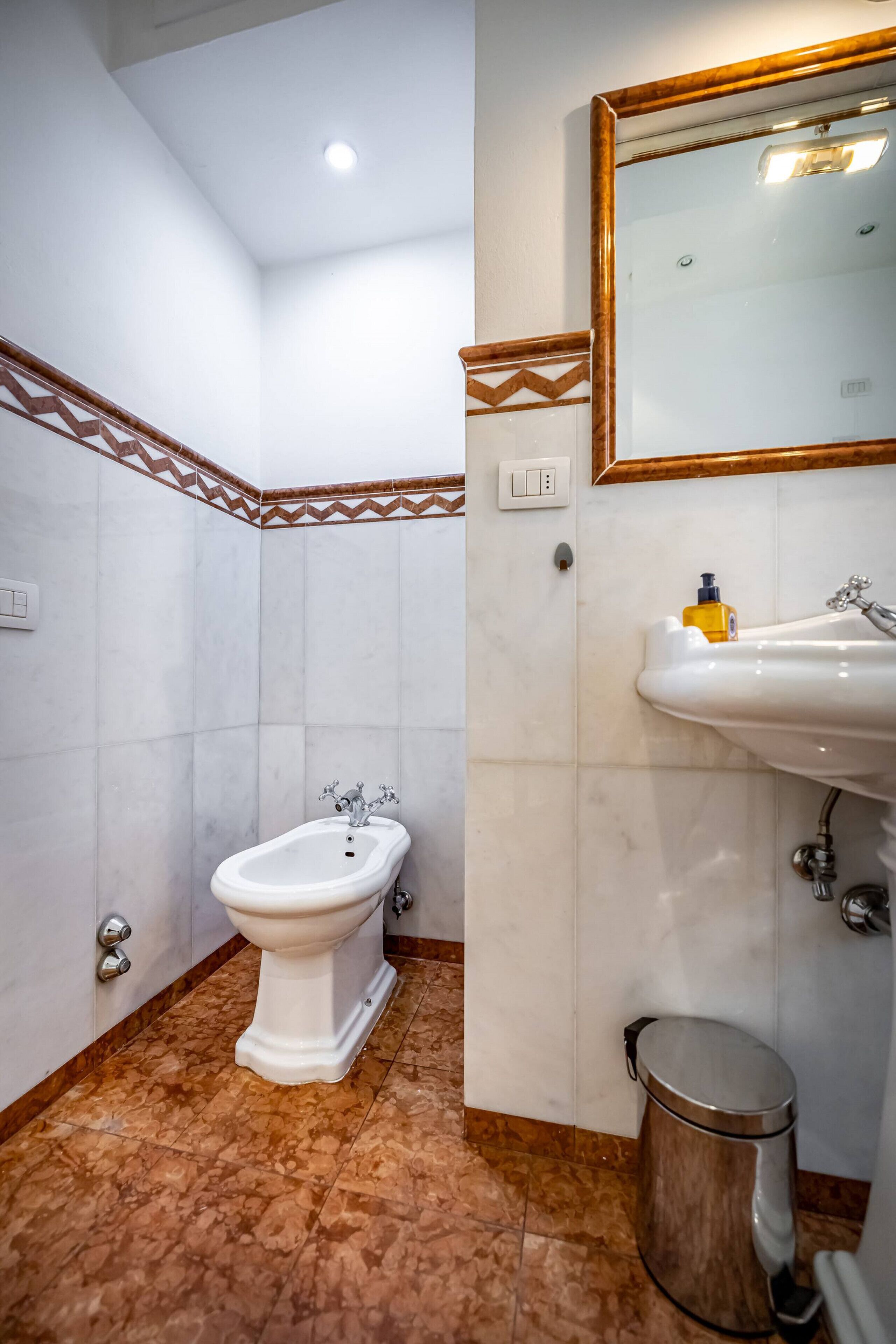 Un baño con bidé, lavamanos y espejo.