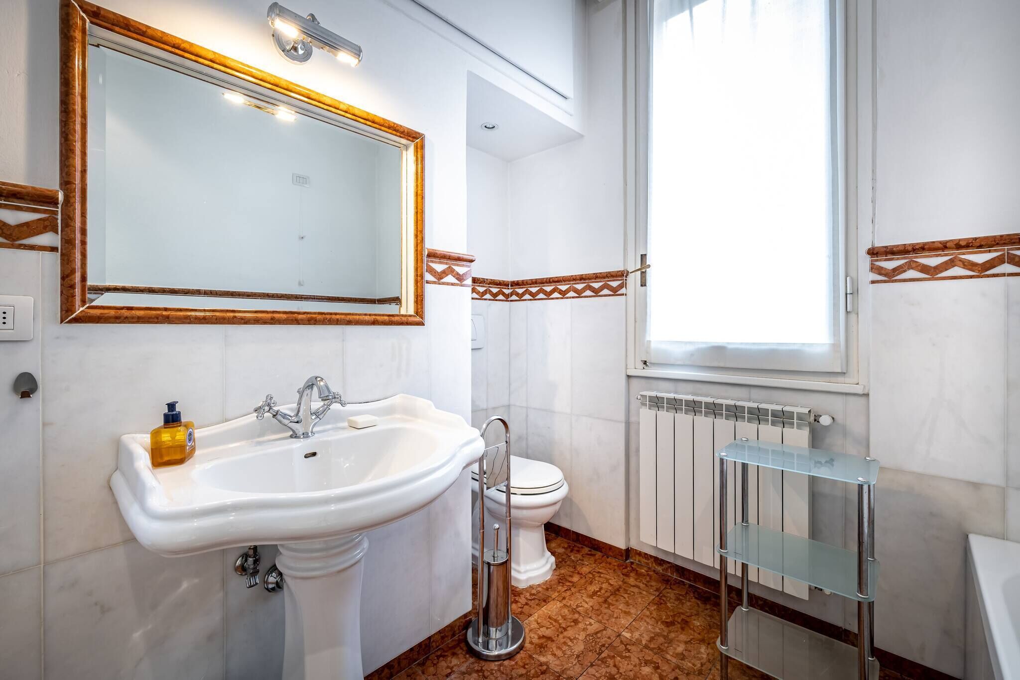 A bathroom with a white sink, a mirror, a toilet, and a radiator.
