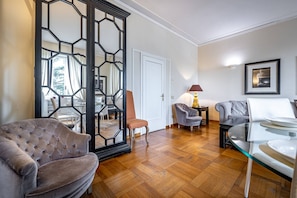 Ein modernes Wohnzimmer mit einem gepolsterten Sessel, einem Glastisch und einer Couch.