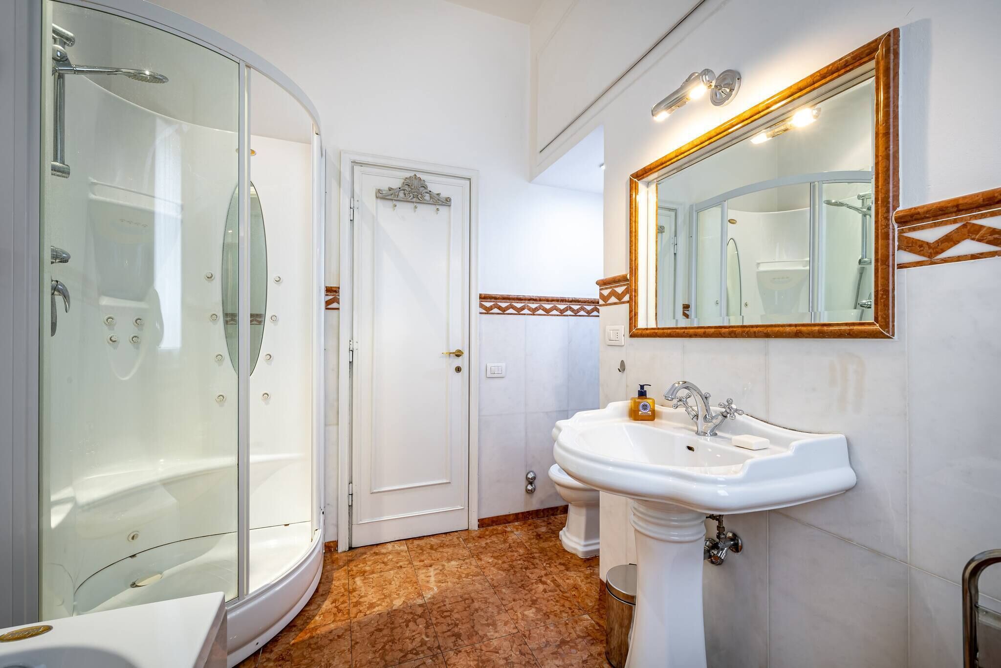 A bathroom with a glass-enclosed shower, a sink, and a mirror.