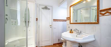 A bathroom with a glass-enclosed shower, a sink, and a mirror.