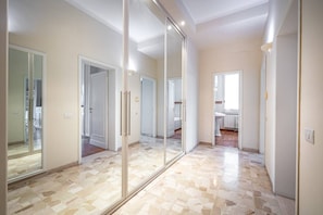 Ein geräumiger Flur mit Fliesenboden, spiegelnden Schranktüren und Blick ins Badezimmer.