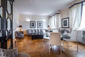Una sala de estar moderna con un sofá, sillas, una mesa de vidrio y cuadros enmarcados en la pared.