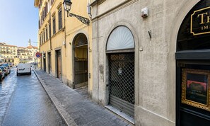 A street view with a building featuring a large arched entrance, a visible number '9' sign, and a black-framed window with a gold frame. - Fossi (Florence)