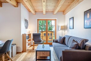 A living room with a wooden ceiling, a sofa, a chair, a coffee table, and a bookshelf. - Apartment 'Bergluft' with Mountain View, Private Terrace and Wi-Fi (Feldberg)
