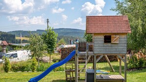 Un parc infantil amb tobogan i una caseta de fusta.