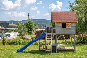 A playground with a slide and a wooden playhouse. - Apartment 'Bergluft' with Mountain View, Private Terrace and Wi-Fi (Feldberg)