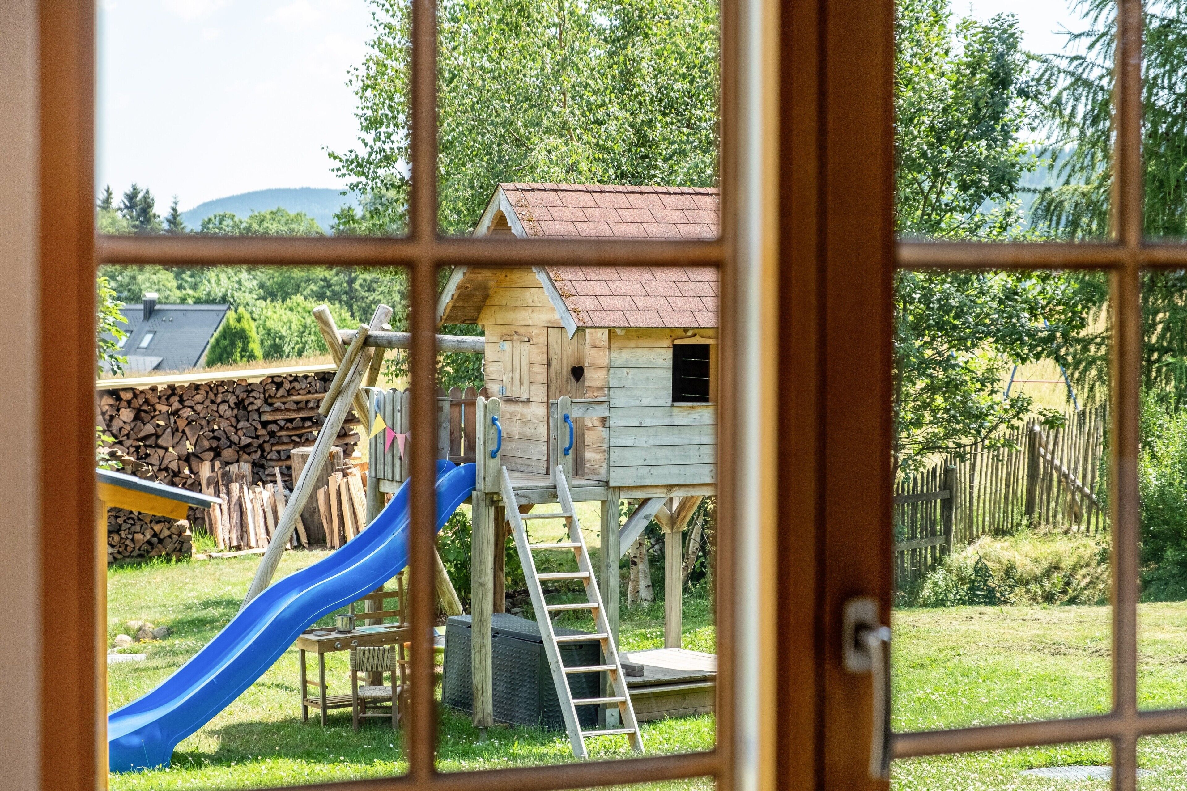 A wooden playhouse with a slide and a ladder.