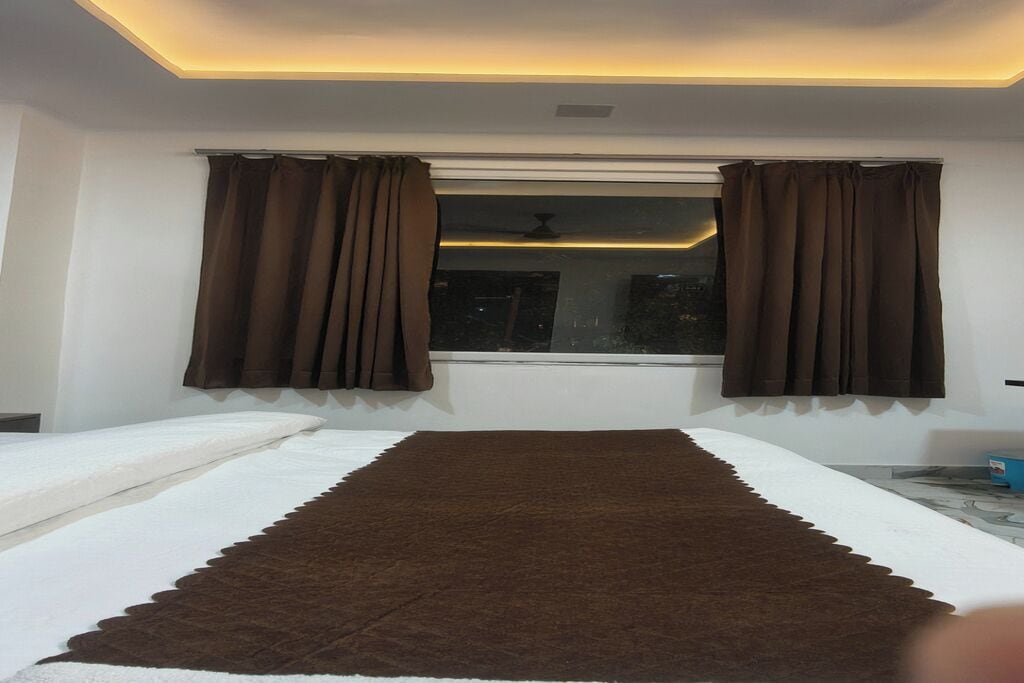 Een slaapkamer met een bed, een raam met gordijnen en een plafondlamp.
