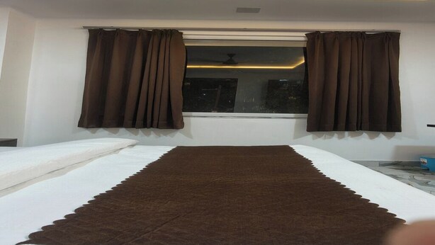 A bedroom with a bed, a window with curtains, and a ceiling light. - Hotel Rudra Haridwar (Haridwar)