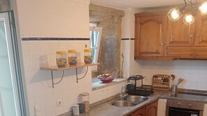 Uma cozinha com bancada de granito, dois bancos, pia, fogão e armários de madeira.