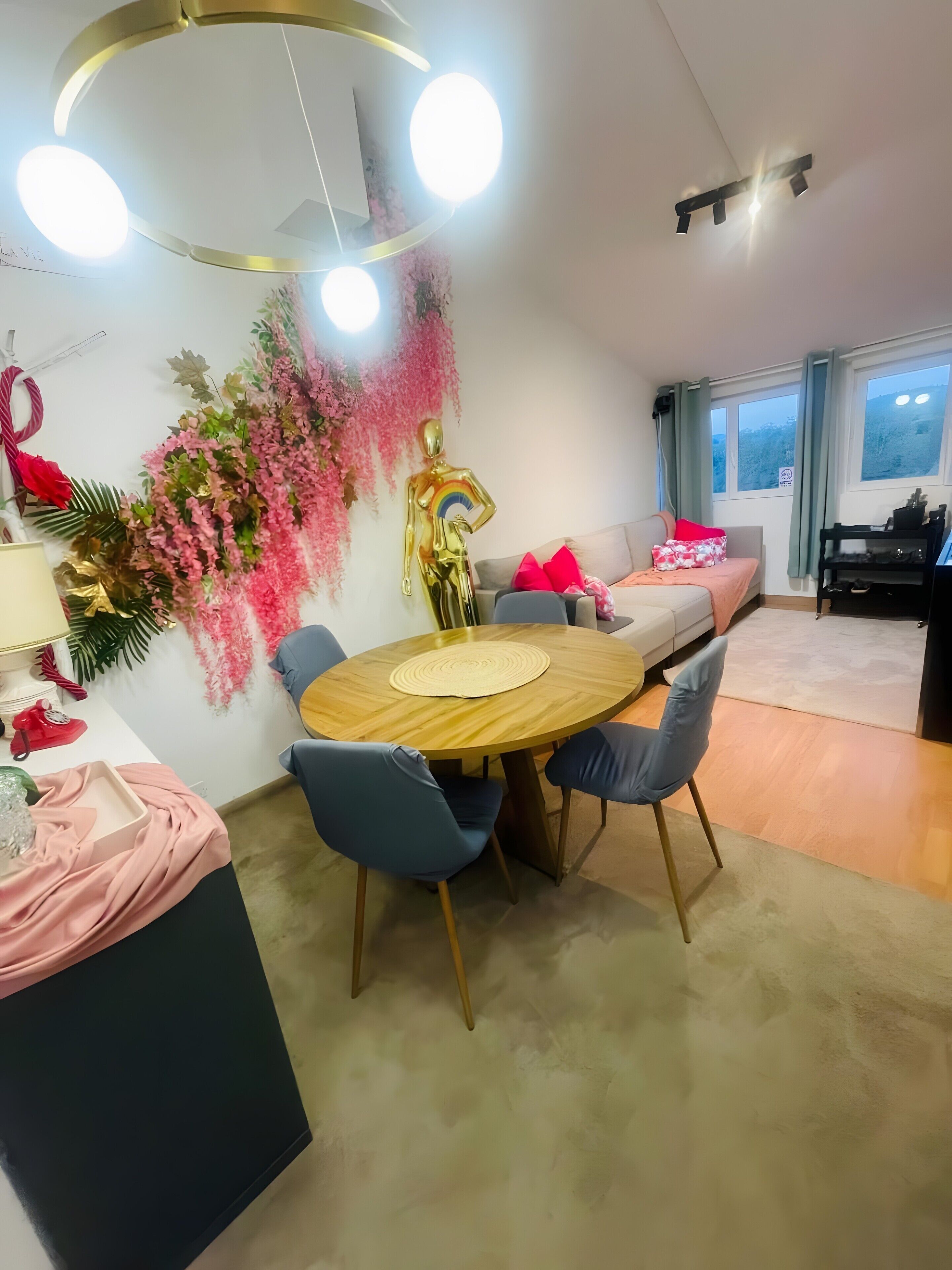 Una sala de estar moderna con comedor, un sofá, una mesa y sillas, y una pared decorativa.