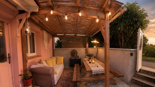 Eine Terrasse im Freien mit einem Holztisch, einer Couch und einer Buddha-Statue.
