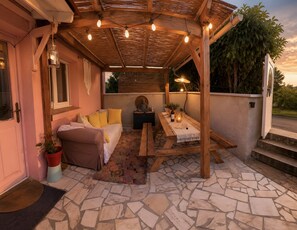 An outdoor patio with a wooden table, a sofa, and a Buddha statue. - Maison donarosa charmante (Vieille-Brioude)