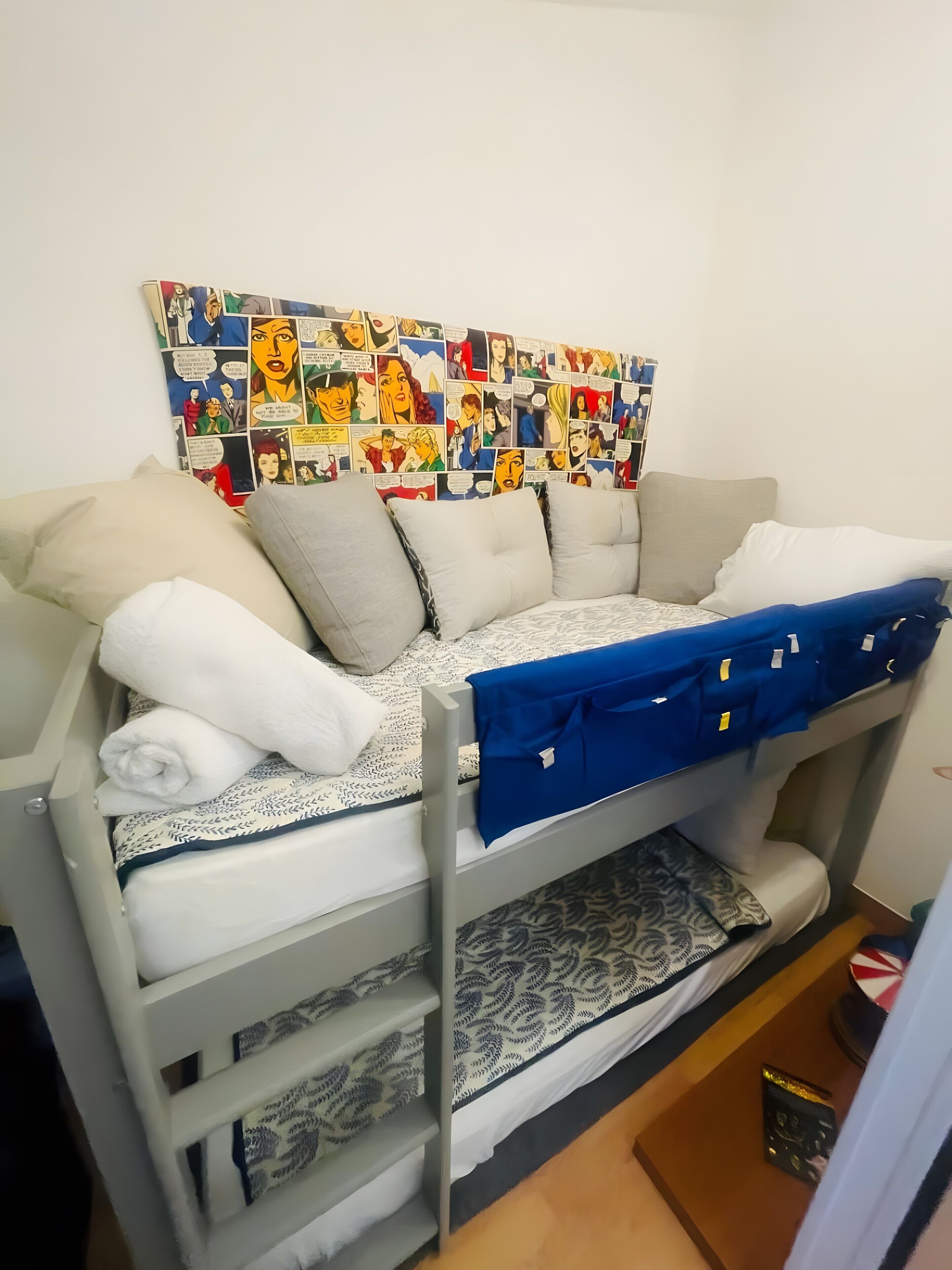 Ein Stockbett mit Wandbildern im Comic-Stil, einer gemusterten Bettdecke und einer blauen Decke.