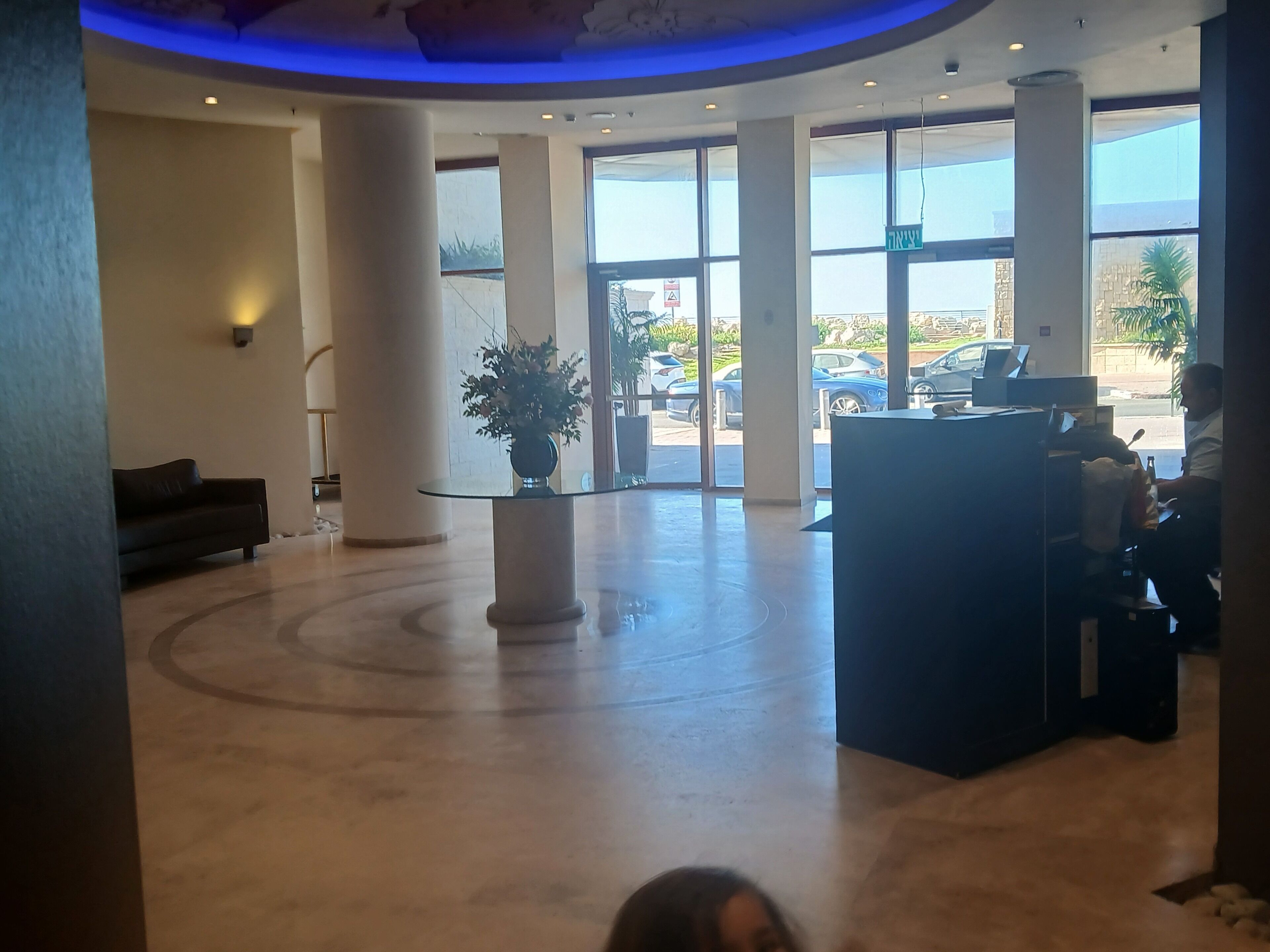 A lobby with a reception desk, a potted plant, and a sofa.