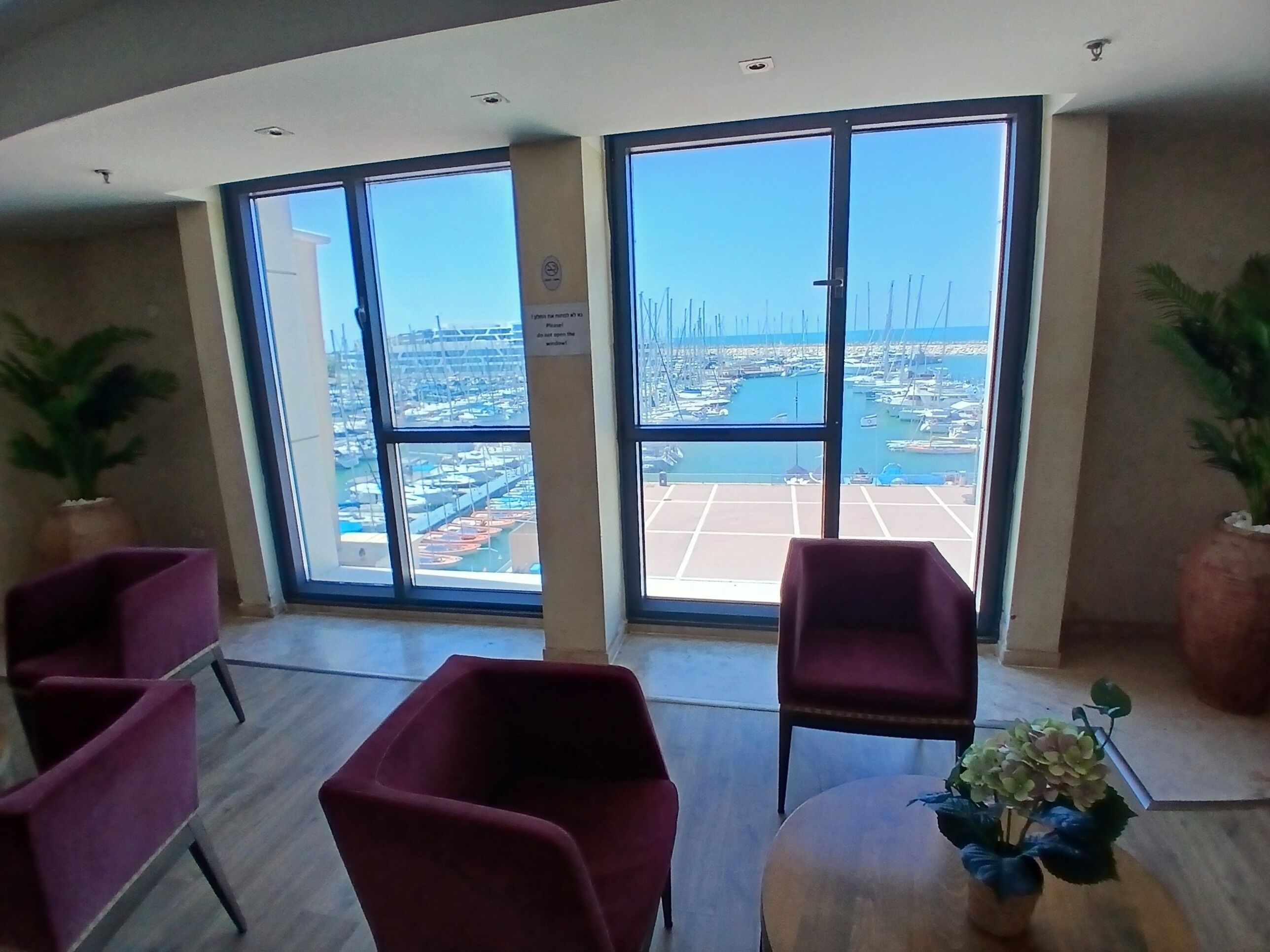 A room with large windows, a view of a marina, and several purple chairs.