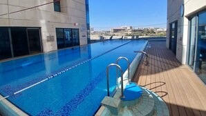 A swimming pool with clear blue water, surrounded by a wooden deck and modern architecture.