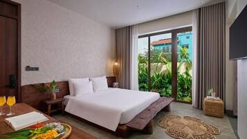 A hotel room with a bed, bedside table, and a view of greenery outside.