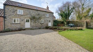 Une maison en pierre avec une allée en gravier et un jardin clos.