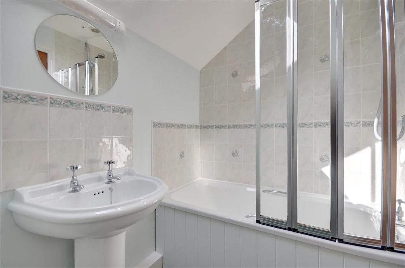 Un bagno con lavandino, specchio e vasca da bagno bianchi.