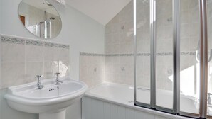 Une salle de bain avec un lavabo blanc, un miroir et une baignoire.
