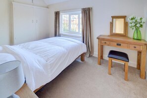 A bedroom with a bed, a wooden desk with a chair, a mirror, and a vase with flowers. - 1 Bed in Whitby (oc-w950) (Whitby)