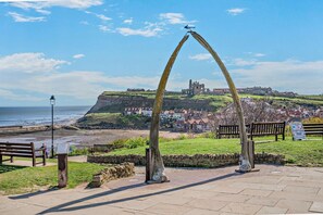 A coastal town with a prominent arch monument, benches, and a view of a historic building on a hill. - 1 Bed in Whitby (oc-w950) (Whitby)