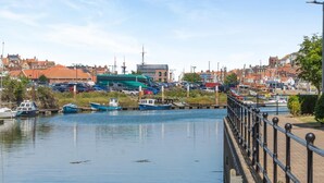 Vista al agua con barcos amarrados, un puente y edificios al fondo.