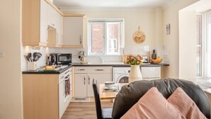 Una cocina moderna con armarios blancos, microondas y ventana con vista a un muro de ladrillo.