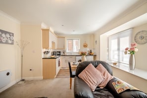 A compact living space with a kitchenette, a dining area, and a sofa with cushions. - 1 Bed in Whitby (oc-w815) (Whitby)