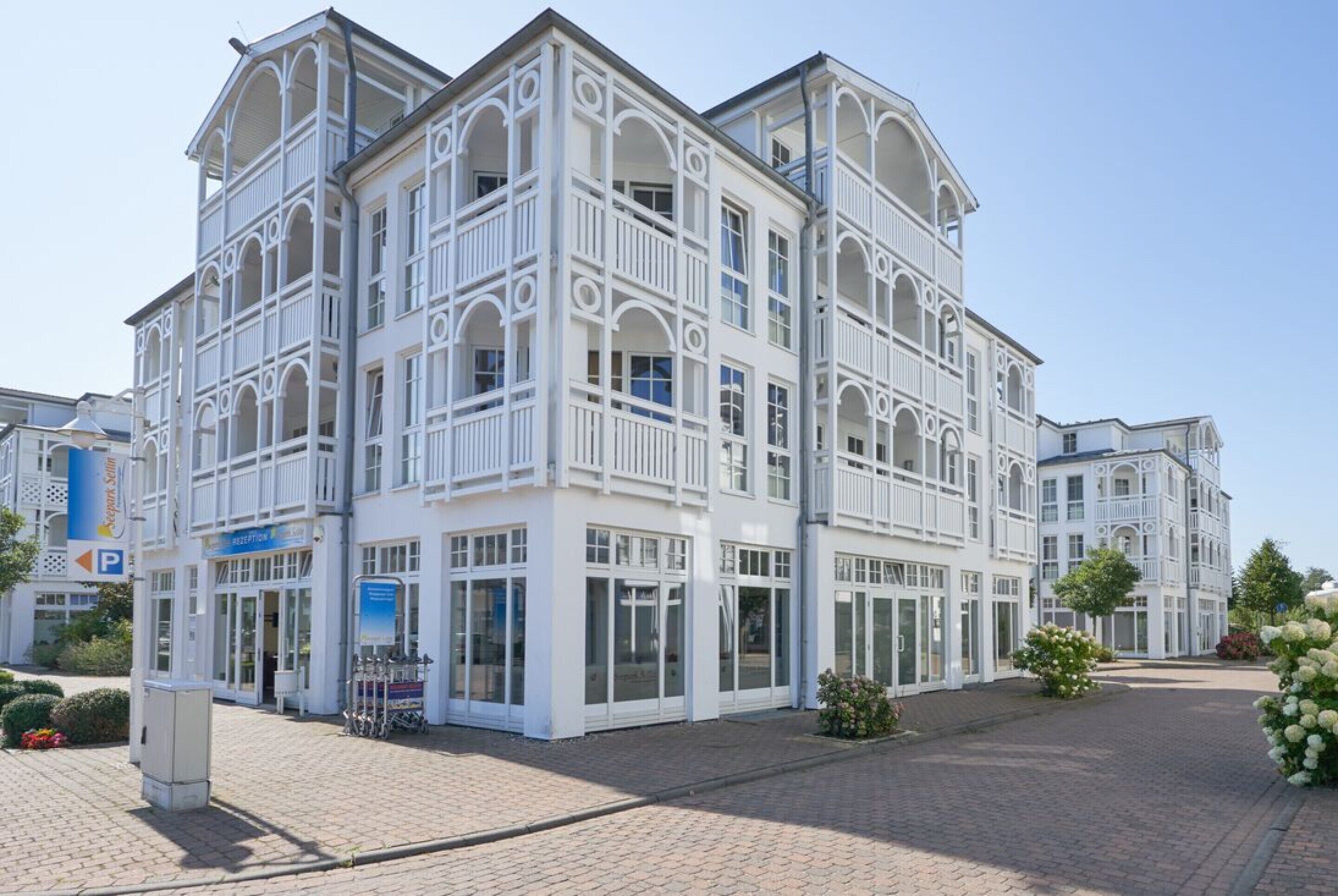 Een hotel met meerdere verdiepingen, een witte gevel, balkons en een receptie.