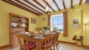 Un comedor con mesa de madera, sillas y vistas al exterior.